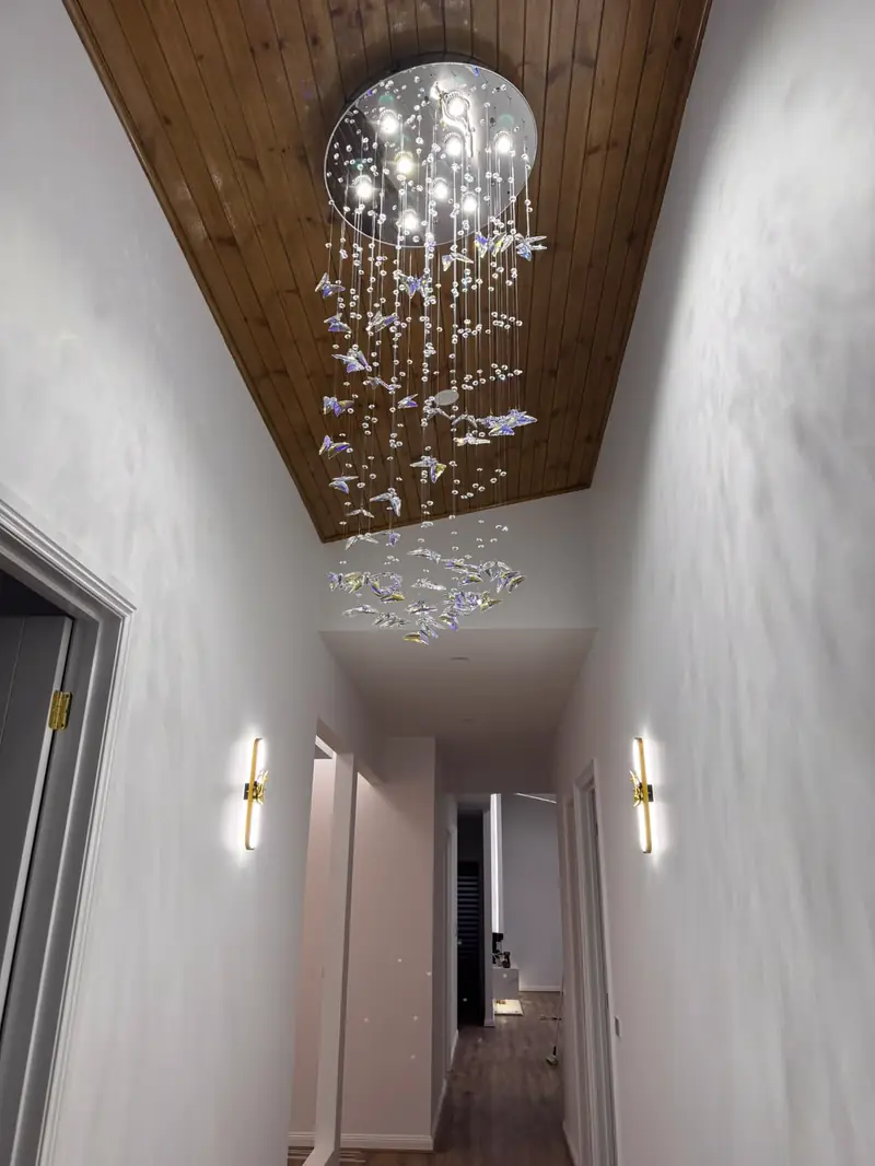 Entry hallway with timber-lined ceiling, wall sconces and crystal chandelier