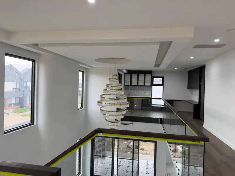 Double-height void with layered ceiling bulkheads and a statement chandelier