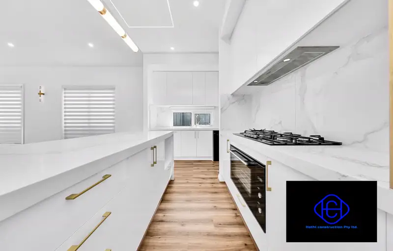 Galley Kitchen — Marble benchtops, gold hardware and a full-height splashback.